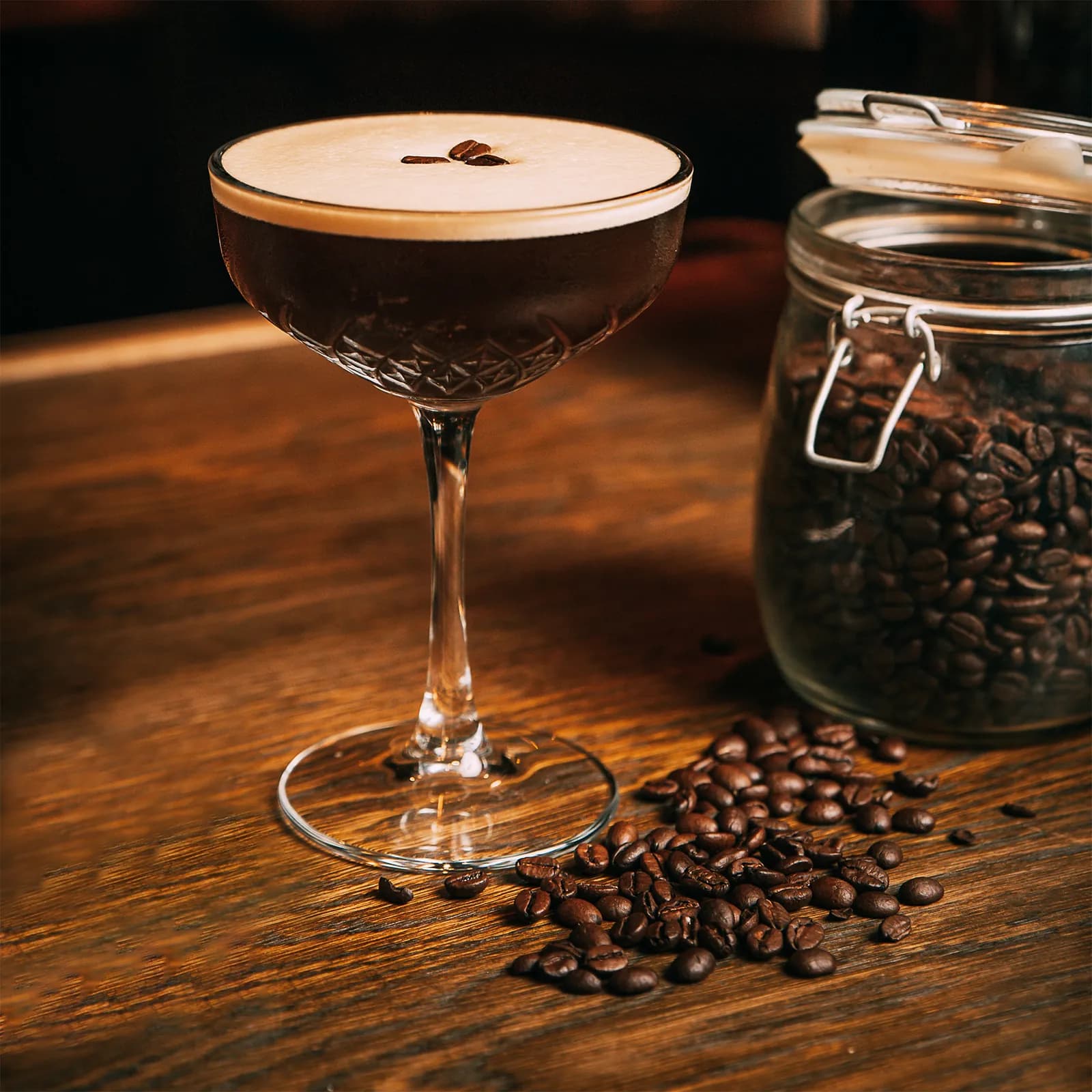 Poured Spark Plug espresso martini with a jar of coffee beans