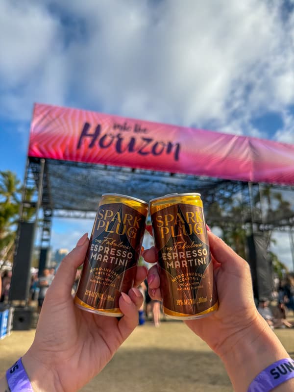 Two cans of Spark Plug nitro espresso martini in front of the Horizon Fest stage